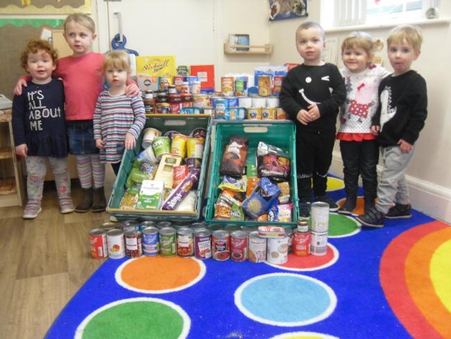 Puddleducks nursey children with some of the harvest festival whihc they donated to the foodbank